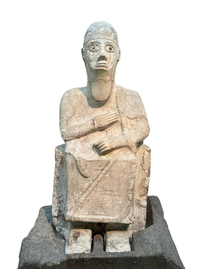 The dolomite Statue of Idrimi on display at the British Museum, its surface covered in cuneiform inscription.
